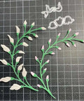 3 Piece Flower Leaf Branches Metal Die Cuts Set For DIY Embossing And Card Making with floral leaves frame stencils on a grid mat.