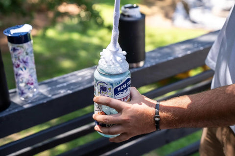 Person using Drill Powered Bottle Brush Cleaner For Water Bottles Mugs Cups Pots Glasses Jars Blenders And Pitchers White And Blue Kitchen Cleaning Accessory With Deep Scrub Power And Quick Connect for cleaning jar outdoors.