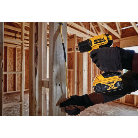 Person using Cordless Heat Gun With LED Light And Lock On Convenience, No Cord, All Power, Hits Up To 990 Fahrenheit, Roughly 42 Minutes Runtime Per Charge, Includes Flat And Hook Nozzle Attachments, Tool Only DCE530B in a construction site