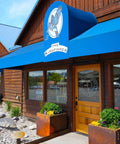 The Kingfisher store exterior with blue awning and wooden facade under a clear blue sky.