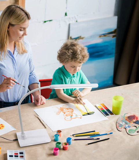 Child painting under Uno LED Art And Craft Table Lamp With Independent Switch Flexible Arm And Single Adjustable Head For Precise Daylight Lighting White Finish For Your Desk Studio Or Craft Setup.