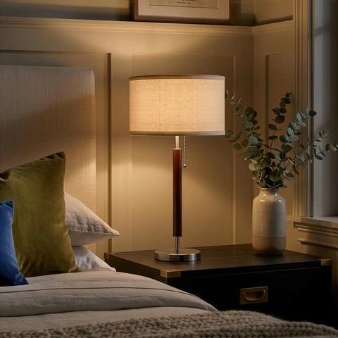 Carter LED Bedside Lamp with Soft Ambient Glow on nightstand, stainless steel and walnut finish, soft light illuminating bedroom.