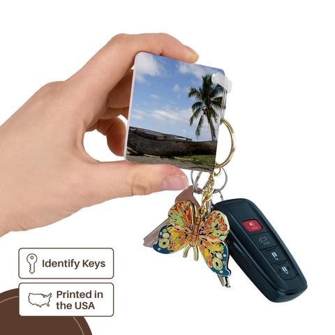 Outrigger Fishing Canoe Key Chain Set From Fiji Bright Multicolor Print Heavy Duty Plastic High Gloss Finish Dual Sided Image Includes Hardware 2 Pack held in hand