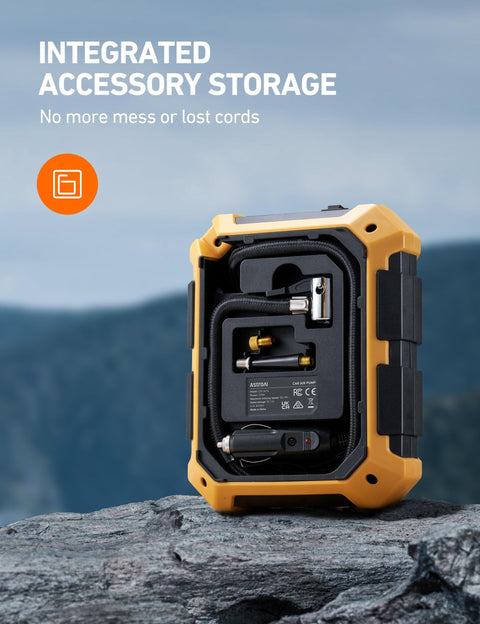 Back view of 12V DC Portable Tire Inflator With LED Light And Digital Gauge showing integrated accessory storage on rocky surface.