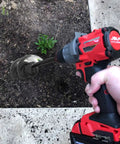 Hand holding drill with Garden Auger Drill Bit For Bulbs And Bedding Plants, 1.8 By 15 Inch, digging soil in garden bed.
