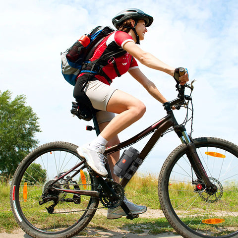 Cyclist on bike with Go-To Golf Cart Speaker Mount With Adjustable Straps Bluetooth Wireless Holder attached to frame.