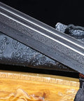Close-up of Beefy Damascus Tang Dao Sword with black gold finish, showing traditional folding pattern and alloy fittings.
