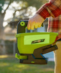 Person holding 20-Volt Cordless Handheld Seed And Fertilizer Spreader For Yard Work With Adjustable Spreading Rate Dial