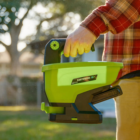 Person holding 20-Volt Cordless Handheld Seed And Fertilizer Spreader For Yard Work With Adjustable Spreading Rate Dial