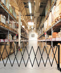 Tough 11.5 Foot Expandable Barricade Gate And Retractable Metal Crowd Control Fence With Smooth Rollin Wheels in warehouse aisle.
