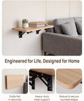 Slick Folding Wall Mounted Projector Shelf In Solid Natural Wood, showing compact design with succulent and books on a gray couch.