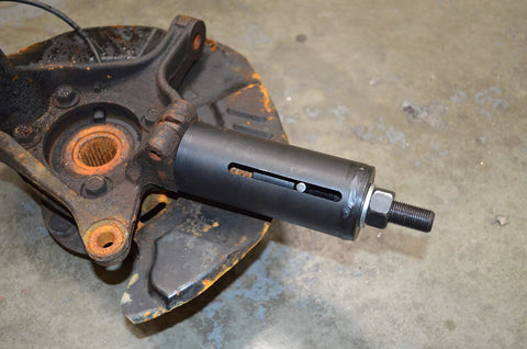 Astro Tools 78620A ball joint puller remover, side view of black tool installed in a rusted wheel hub.