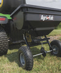 Tow Behind Broadcast Spreader With 85 Lb Capacity For Lawns, 10 Foot Spread, Covers Up To 14,000 Sq Ft, attached to a tractor.