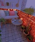 Outdoor balcony with brown reed fence roll privacy screen, decorated with lights, plants, and a cozy seating area, 4 ft by 16.4 ft.