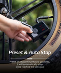 Hand using On The Go Portable Electric Mini Bike Pump With 130 PSI Gauge Auto Stop Digital Pressure Display for bike tire