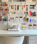 All In One Pegboard Organizer Kit 42 Pack With Large Baskets Bins Cups Hooks J And L Book Holder Wall Mount Storage For Craft Room Office Garage Shed White Pink installed above sewing desk.