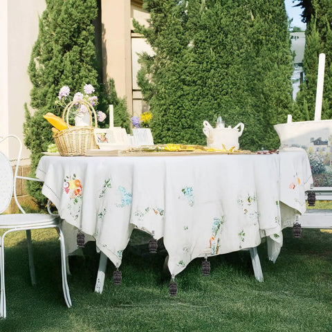 Outdoor table with tablecloth secured by Owl Shaped Cast Iron Tablecloth Weights Set Of Eight, waterproof finish against trees.