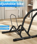 Heavy Duty Indoor Bike Floor Stand Adjustable Single Wheel Rack For Garage Ready Setup Fits 16 To 29 Inch Wheels And Up To Three Point Five Five Inch Tire Width Ideal For Mountain Road BMX And City Bikes shown on wooden floor indoors.