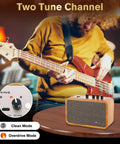 10W Mini Guitar Amp With Clean And Drive Channels on table, musician playing bass, USB-C rechargeable, headphone jack, wood finish