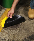 Person placing Beefy Heavy Duty Storm Drain Cover For Round Drains Up To 6 Inches Diameter on outdoor drain, showing vinyl top.