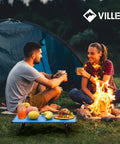 Ultralight Folding Beach Table For Camping And Picnics set up beside campfire with food, in use outdoors