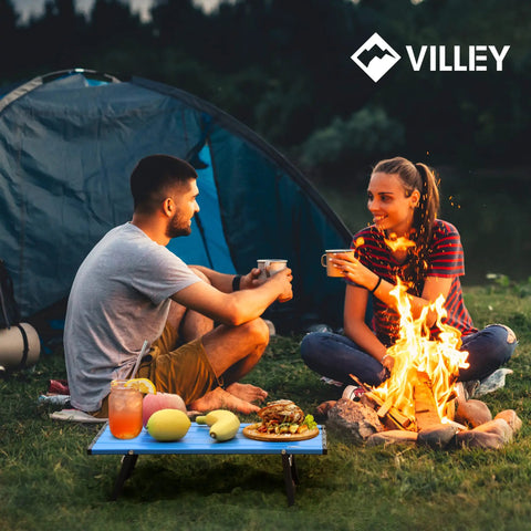 Ultralight Folding Beach Table For Camping And Picnics set up beside campfire with food, in use outdoors