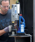 Front view of Hougen HMD905 115V magnetic drill with coolant bottle mounted on a metal worktable