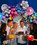 Party with friends in front of 135 Piece Disco Balloon Arch Kit With Silver Blue Green Purple Hot Pink And Gold Metallic Balloons And Star Foil Balloons For Birthday Parties And 70s 80s 90s Retro Disco Decor And Photo Backdrops.