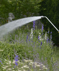 RelaxGrip Water Wand With GentleRain Shower Head 33 Inch Reach watering plants in a garden, featuring 1004 ultra fine spray holes.