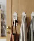 Slick Rustic White Cast Iron Wall Mounted Hooks With Screws And Anchors Shabby Chic Door Knob Decor for bags and coats on a wood door.