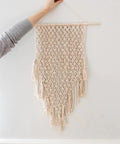 Hand holding 4mm Natural Cotton Macrame Rope Twisted 3-Strand Cord, 328 Yards For Wall Hangings displayed on wall.