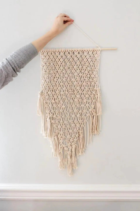Hand holding 4mm Natural Cotton Macrame Rope Twisted 3-Strand Cord, 328 Yards For Wall Hangings displayed on wall.
