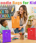 Teacher handing a 50 Pack Multicolor Party Favor Gift Bags 8x11 Inches With Handles Reusable Plastic Goodie Bags to a student.