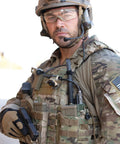 Soldier using Sidewinder 55 Lumen Compact II Military Flashlight with Helmet Mount on tactical vest, outdoors.