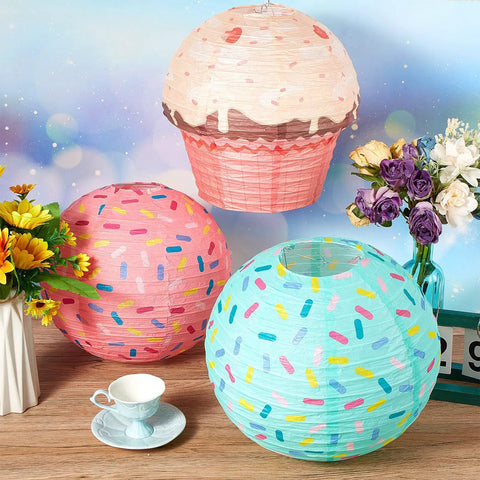 Six Pack Donut Party Hanging Paper Lanterns With Sprinkle Cupcake Designs for Birthday Party and Baby Shower Decor displayed on table.