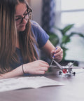 Person assembling Build Your Own Fighter Jet Erector Set Metal Model Airplane Kit with Detailed Instructions on table