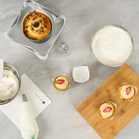 Baking setup with pastries and ingredients using Greaseproof Cupcake Liners 4000 Pack, 4 Oz Disposable Muffin Cups For Oven Or Freezer.