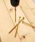 Drill inserting 5-inch deck screw through wood, showcasing 50 Pc Deck Screws Set, 5 Inch #10 Self Drilling Wood Screws With Rust Resistant Coating
