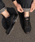 Person wearing Men's Steel Toe Work Sneakers Comfortable Lightweight Safety Shoes With Breathable Mesh on asphalt