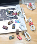 Leather Cord Organizer And Cable Keeper Case for Earbuds and Headphones, USB Holder, Velcro Cable Ties on a laptop desk.