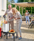 Outdoor gathering with Powerful Portable Propane Stove With Foldable Side Rack Single Burner preparing turkey by patio.