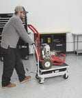 Strongway hydraulic lift table cart on red steel frame with casters carrying a small engine
