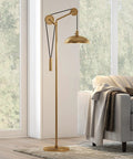 Solid Wheel Pulley Floor Lamp With Brass Dome Shade And Industrial Steel Base in a living room setting