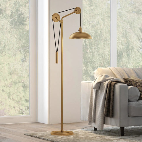 Solid Wheel Pulley Floor Lamp With Brass Dome Shade And Industrial Steel Base in a living room setting