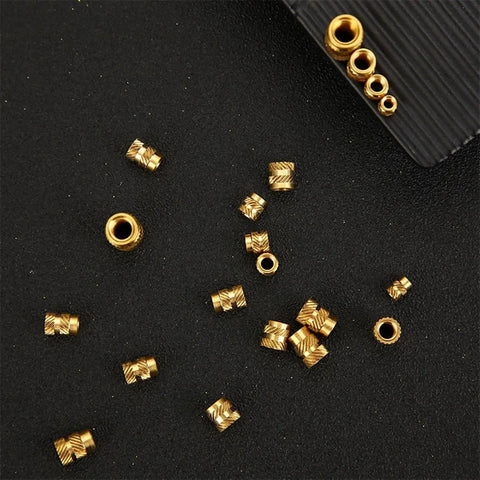 Solid Brass Hot Melt Nuts With Double Twill Knurl Grip For High Torque Stress Loads. Pack Of 20 Pieces scattered on a black surface.