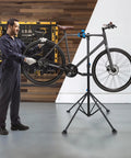Mechanic using Adjustable Bike Repair Stand For Home Use, Heavy Duty Bicycle Maintenance Stand Supports Up To 66 Lbs