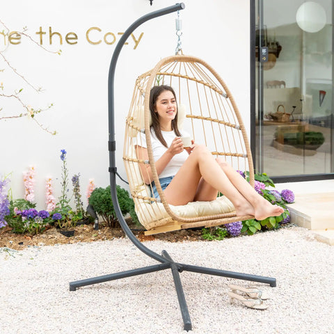 Woman relaxing in Hanging Egg Chair With Stand And Footrest For Indoor Outdoor Use in garden setting.