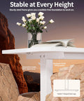 Sleek BIZUM Electric Standing Desk 60 x 24 Inch White with sturdy steel frame and lifting system displayed with flowers and rocks.