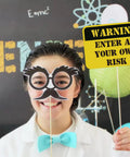 Child wearing mad scientist glasses from 12 Piece Science Photo Booth Props With Sticks Mad Scientist Selfie Cards Chemistry Lab Party Supplies