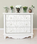 Dresser with Treetops Peel And Stick Wallpaper In White And Off White, featuring tree motif design for easy DIY decor; flowers on top
